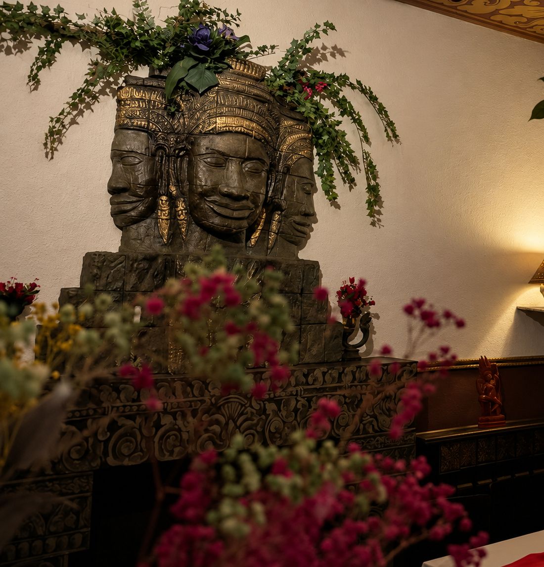 Skulptur eines Bayon-Kopfes mit Blumen im Gastraum