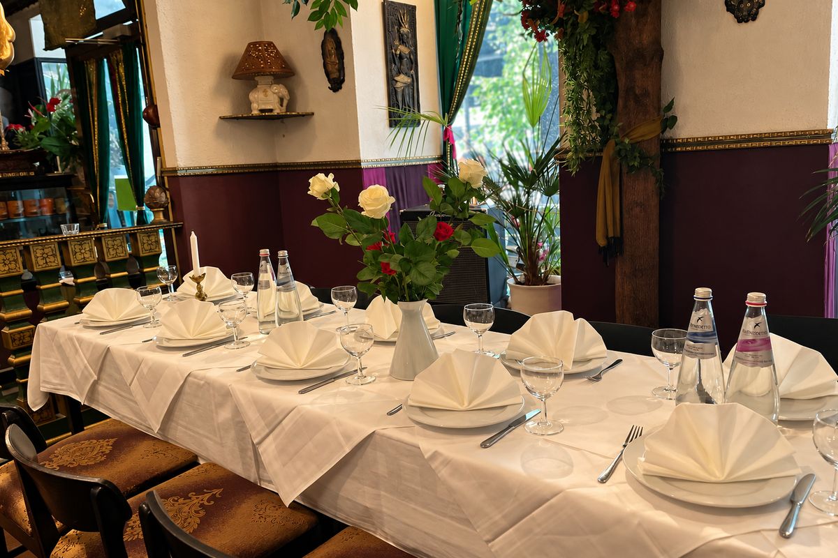 Festlich gedeckte weiße Tafel mit Rosen und gefalteten Servietten